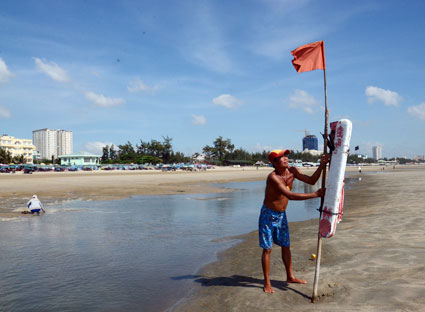 Cứu hộ viên cắm cờ cảnh báo ao xoáy trên bãi biển Thùy Vân. Ảnh: MỸ LƯƠNG