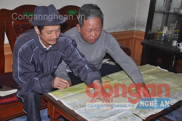 Ông Hanh (bên phải) và đồng đội bên tấm bản đồ theo ông đi khắp mọi nẻo đường tìm hài cốt liệt sỹ