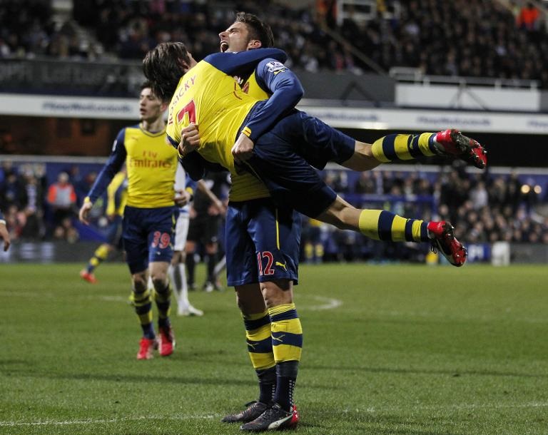 Tiền đạo người Pháp Olivier Giroud của Arsenal (đứng) ăn mừng bàn thắng cùng đồng đội Tomas Rosicky trong trận đấu thuộc khuôn khổ Giải bóng đá Ngoại hạng Anh giữa hai CLB Queen's Park Rangers  và Arsenal tại sân vận động Loftus Road ở London
