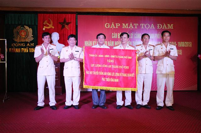 Đại diện Thành ủy, HĐND, UBND, UBMTTQ TP Vinh tặng bước trướng với dòng chữ “phát huy truyền thống Anh hùng lực lượng vũ trang, đoàn kết phát triển vững mạnh” cho Công an TP Vinh.