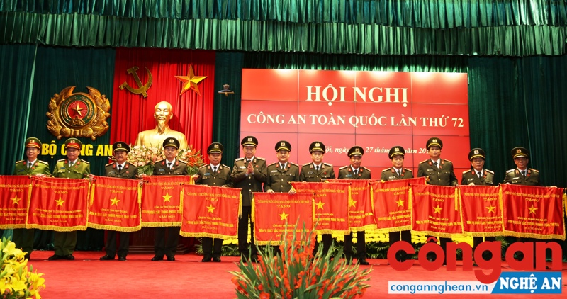 Đồng chí Đại tá Nguyễn Hữu Cầu, Giám đốc Công an tỉnh Nghệ An (thứ 7 từ phải sang) nhận Cờ “Đơn vị dẫn đầu phong trào thi đua Vì an ninh Tổ quốc” của Chính phủ - Ảnh: Quỳnh Vinh
