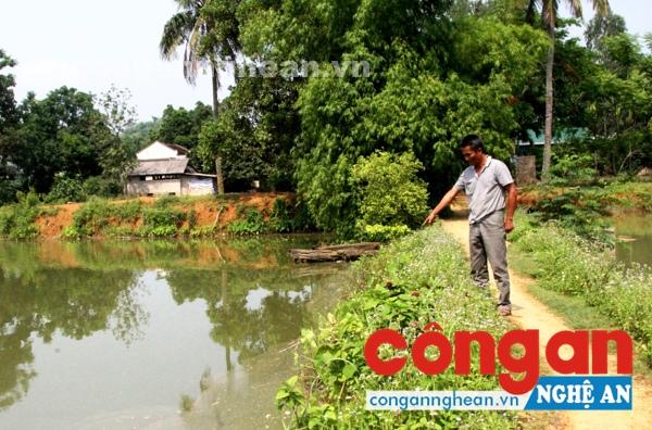 Ông Thước chỉ vị trí bị đổ thuốc diệt cỏ xuống hồ nuôi tôm của gia đình