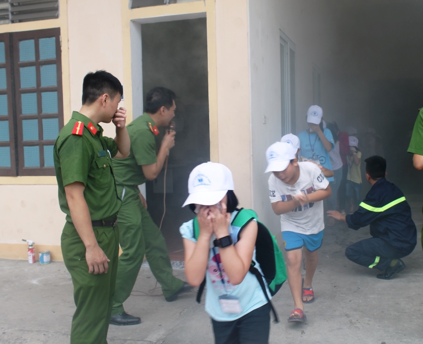 Các em nhỏ cúi khom người, dùng khăn bịt mặt thoát ra khỏi khu vực cháy một cách nhanh chóng