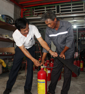 Anh Hoàng Minh Quý, Giám đốc Công ty TNHH TM-DV PCCC Minh Hoàng (bìa trái) và nhân viên công ty kiểm tra bình xịt chữa cháy CO2 trước khi bán cho khách hàng.