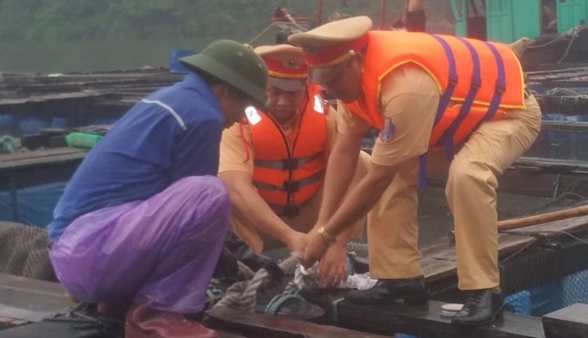Cán bộ Phòng Cảnh sát đường thủy giúp ngư dân chăng buộc lại nhà bè chống bão số 4