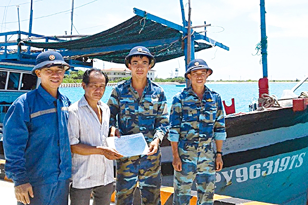 Đại diện Trung tâm HC-KT nghề cá đảo Sinh Tồn phát tờ rơi hướng dẫn ngư trường đánh bắt cho tàu cá PY 96319 TS.