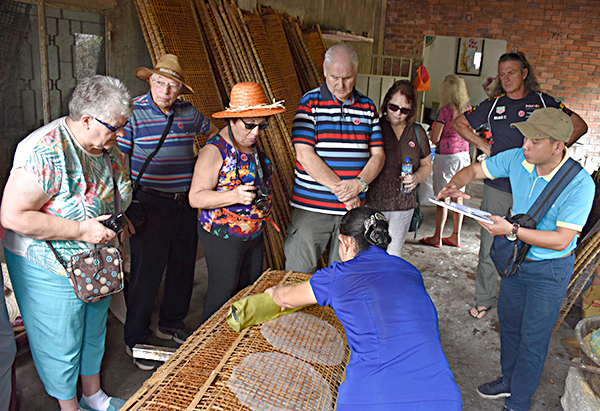 Hướng dẫn viên của Saigontourist (bìa phải) giới thiệu quy trình làm bánh tráng tại một hộ dân ở TP. Bà Rịa cho du khách nước ngoài. Ảnh: MỸ LƯƠNG