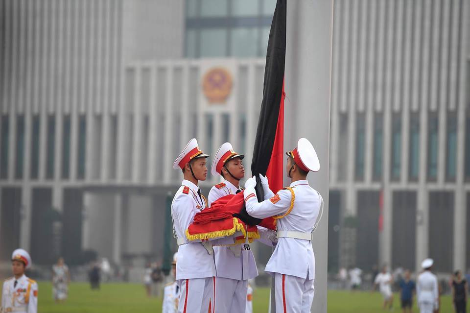 Tiến hành buộc dải băng đen vào cờ Tổ quốc.
