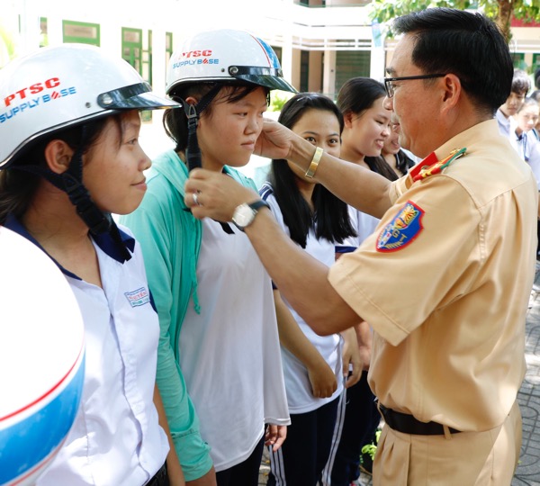 Thiếu tá Nguyễn Duy Bình, Đội trưởng Đội tuyên truyền và Xử lý TNGT (PC08-Công an tỉnh) tặng mũ cho học sinh.