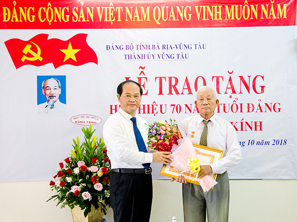 Đồng chí Mai Ngọc Thuận trao Huy hiệu 70 năm tuổi Đảng và tặng hoa chúc mừng đảng viên Lê Kính.