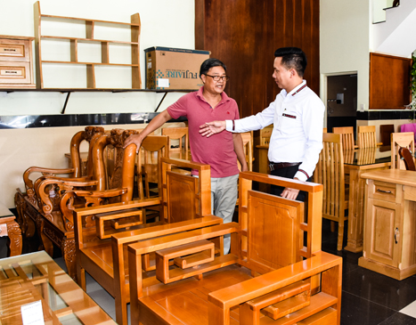 Anh Nguyễn Minh Hiền (bìa phải), giới thiệu các sản phẩm gỗ Đại Hòa Phát cho khách hàng. Ảnh: PHAN HÀ 