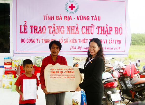 Bà Đinh Thị Trương, Phó Giám đốc Công ty TNHH MTV Xổ số kiến thiết tỉnh BR-VT tặng quà cho gia đình  ông Huỳnh Văn Nhặn (xã Sông Xoài, TX.Phú Mỹ) tại buổi lễ bàn giao nhà “Chữ thập đỏ”. 