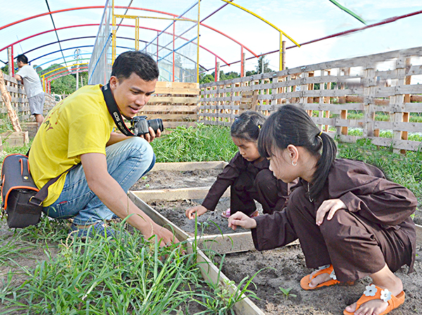 Anh Đặng Anh Tuấn (nhóm Rơm Hý Hoáy) hướng dẫn các em nhỏ cách phân biệt cây rau với cây cỏ.