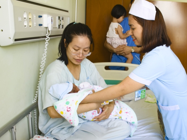 Nữ hộ sinh hỗ trợ sản phụ chăm sóc trẻ sơ sinh.