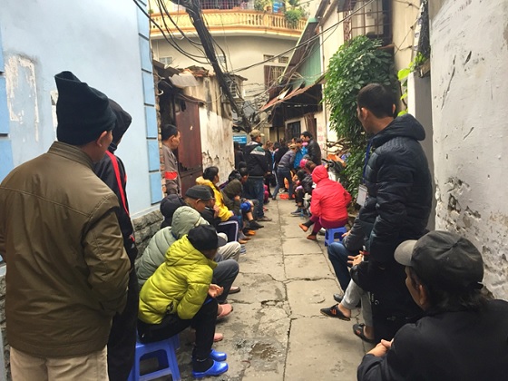 Trong con ngõ nhỏ, mọi người ngồi xếp hàng ngay ngắn, chăm chú lắng nghe đoàn từ thiện đọc đến tên mình để lên nhận quà.