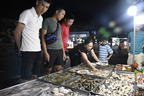 Nhóm du khách chọn mua hải sản tại quán ốc Hai Thành trong khu ẩm thực đêm Long Hải. Ảnh: MINH HIỀN