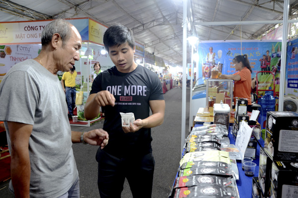 Nhân viên Công ty TNHH Sản xuất và Xuất nhập khẩu cà phê Nón Lá giới thiệu dòng sản phẩm cà phê pha phin giấy cho khách hàng tại hội chợ.