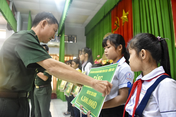 Đại tá Nguyễn Văn Thống, Phó Chính ủy BĐBP tỉnh trao học bổng “Nâng bước em tới trường” cho các em HS.