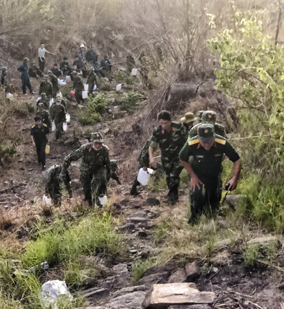 Cán bộ, chiến sĩ LLVT tỉnh mang theo can nước tiếp cận hiện trường để dập tắt vụ cháy rừng le và cây bụi tại khu phố Hải Điền, TT. Long Hải, huyện Long Điền vào tháng 4/2019.