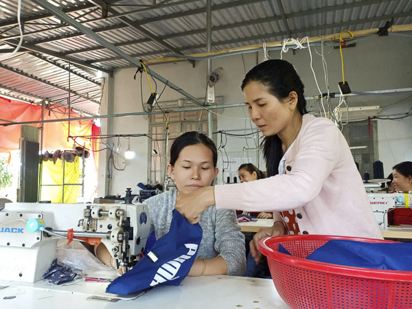 Chị Phùng Thị Thanh Xuân hướng dẫn các chị em may gia công ba lô thể thao tại cơ sở may của gia đình.