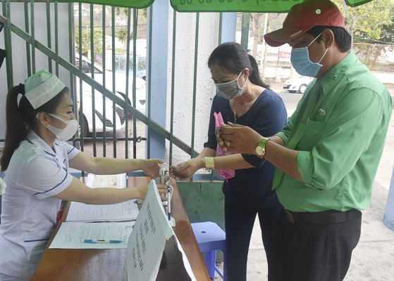 Nhân viên y tế Bệnh viện Lê Lợi hướng dẫn người dân rửa tay sát khuẩn và đeo khẩu trang y tế phòng dịch bệnh COVID-19 trước khi vào bệnh viện khám bệnh. Ảnh: MINH THIÊN