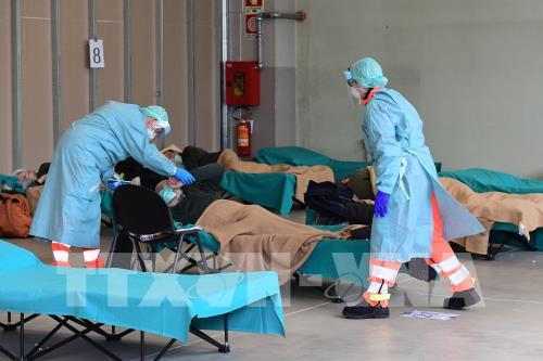 Nhân viên y tế điều trị cho bệnh nhân mắc COVID-19 tại một bệnh viện dã chiến ở vùng Lombardy, Italy ngày 13/3/2020. (Nguồn: AFP)