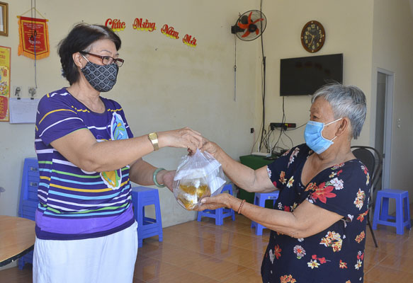 Bà Nguyễn Thị Ngọc Liên (bìa phải) nhận cơm chay miễn phí  của Tịnh xá Ngọc Đức.