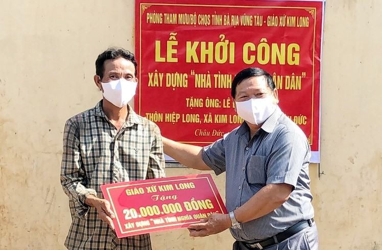Đại diện Giáo xứ Kim Long (bên phải) trao biểu trưng hỗ trợ 20 triệu đồng giúp ông Lê Đình Long xây dựng nhà.