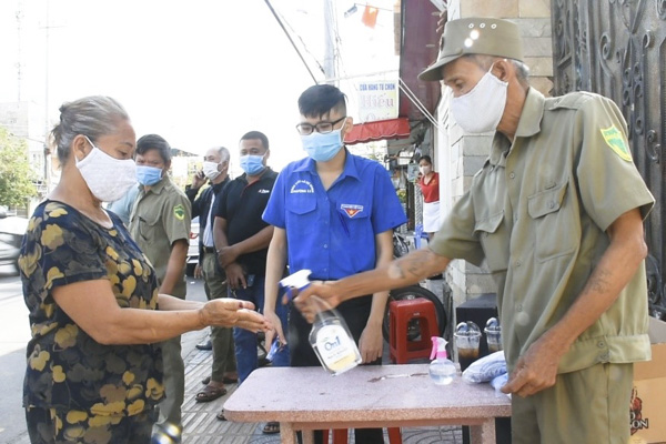 Lực lượng UBND phường 11 hướng dẫn người dân rửa tay sát khuẩn trước khi vào nhận quà. 