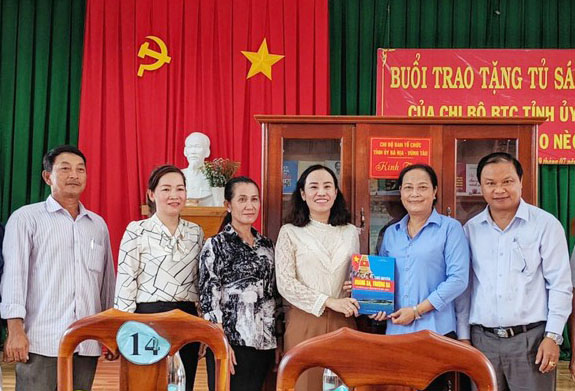 Bà Võ Ngọc Thanh Trúc, Phó Trưởng Ban Tổ chức Tỉnh ủy (thứ 3 từ phải qua) bàn giao tủ sách cho Chi bộ ấp Thèo Nèo.