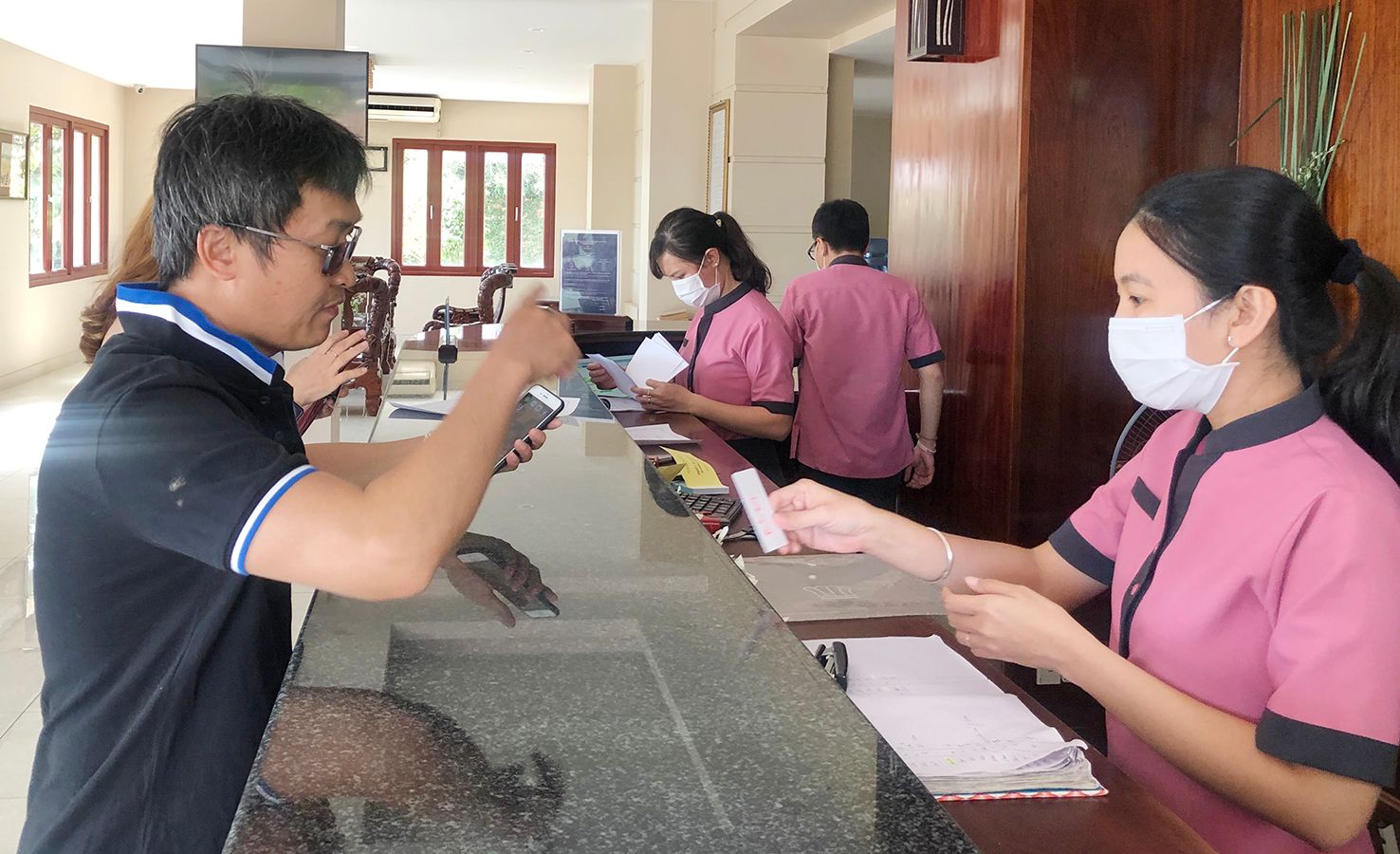 Nhân viên khách sạn Kỳ Hòa mang khẩu trang làm thủ tục nhận phòng cho khách.