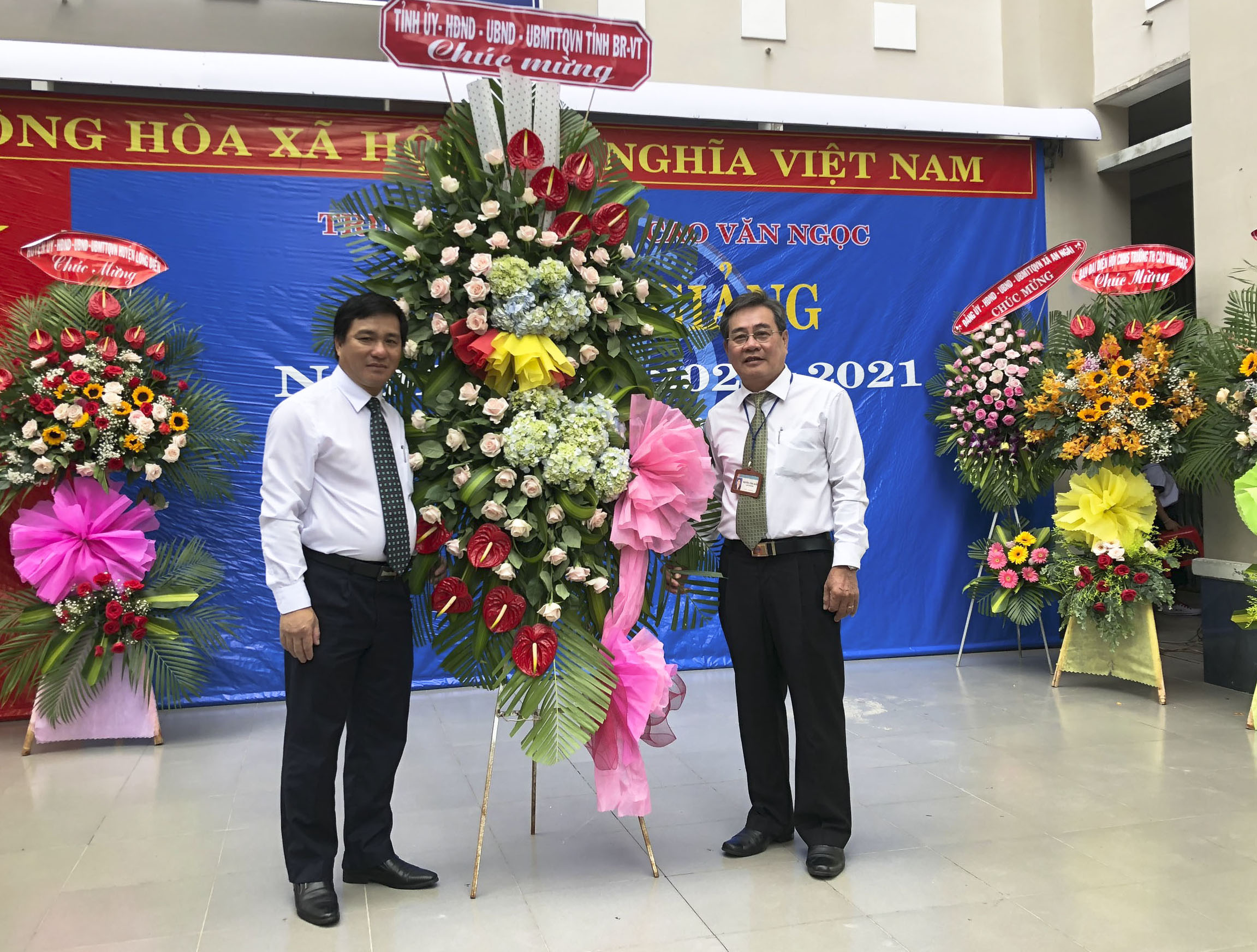 Ông Dương Minh Tuấn, Phó Trưởng đoàn ĐBQH tỉnh (trái) tặng hoa chúc mừng thầy và trò Trường TH Cao Văn Ngọc (Huyện Long Điền). Ảnh: TRÚC GIANG