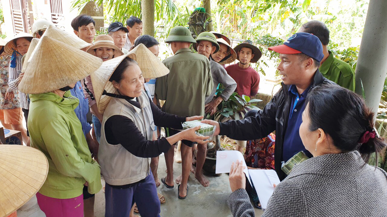 Ông Phạm Ngọc Hải, Chủ tịch Hiệp hội Du lịch tỉnh trao tiền và bánh chưng cho người dân xã Hàm Ninh, Quảng Bình. 