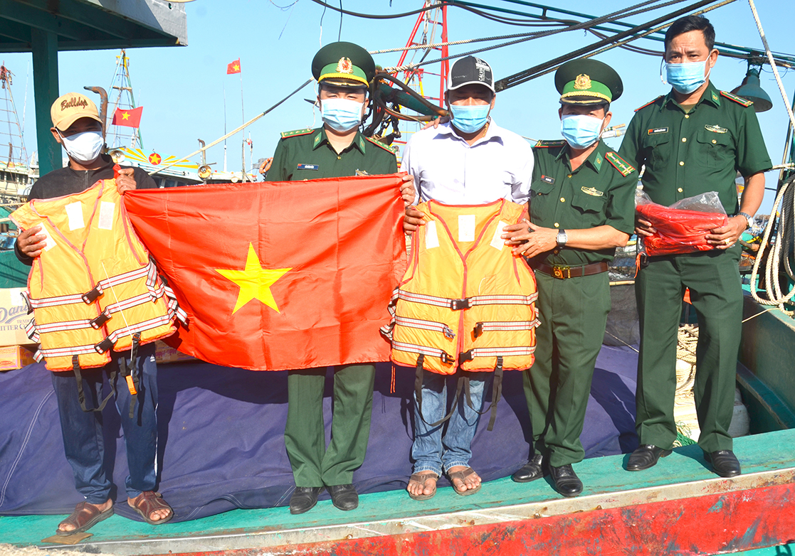 Cán bộ, chiến sĩ Đồn Biên phòng Phước Tỉnh tặng cờ Tổ quốc và áo phao cho tàu cá BV 92788 TS (xã Phước Hưng, huyện Long Điền).