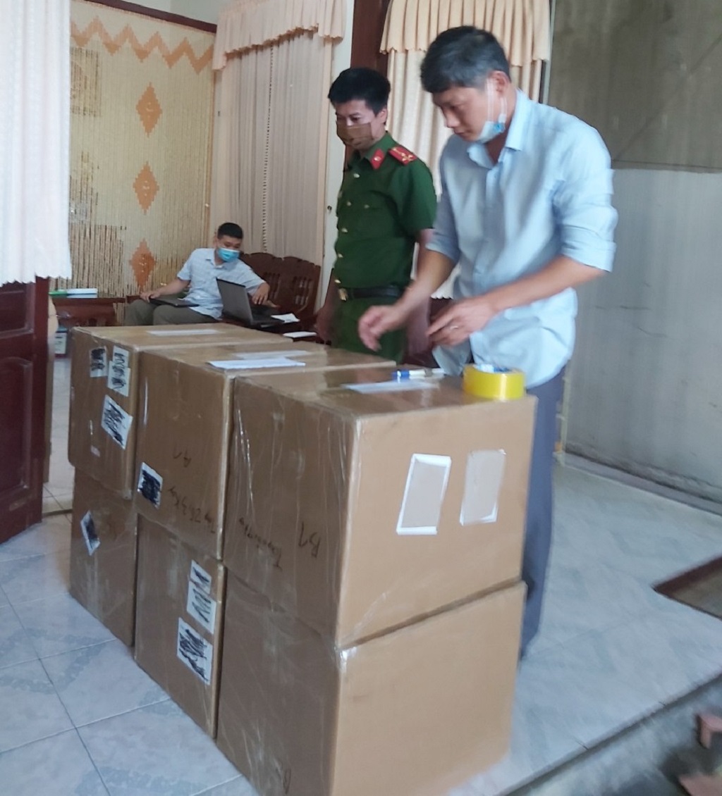 Lực lượng chức năng kiểm tra các thùng cát-tông chứa bộ dụng cụ test nhanh Covid-19