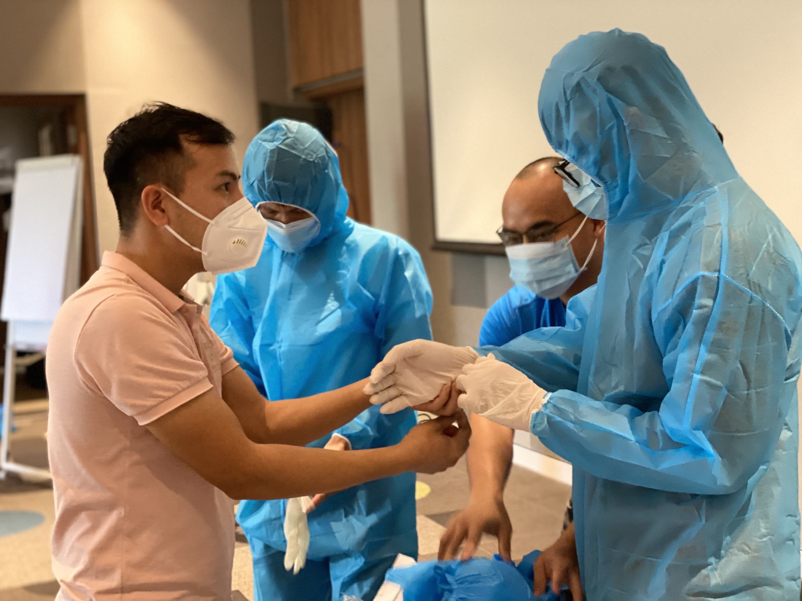 Anh Nguyễn Đức Tâm (trái), nhân viên Khoa Kiểm soát bệnh tật, Trung tâm Y tế TP. Vũng Tàu hướng dẫn cách mang bao tay cho nhân viên khách sạn Ibis Styles.