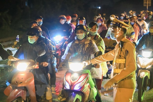 Lực lượng chức năng hướng dẫn đoàn xe giảm tốc độ, xuống xe khai báo y tế khi vào địa bàn Hà Nội. Ảnh: TTXVN