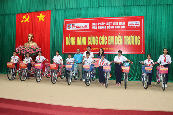 Đại diện Báo Pháp luật Việt Nam - khu vực Đông Nam Bộ và lãnh đạo huyện Đất Đỏ trao xe đạp cho học sinh.