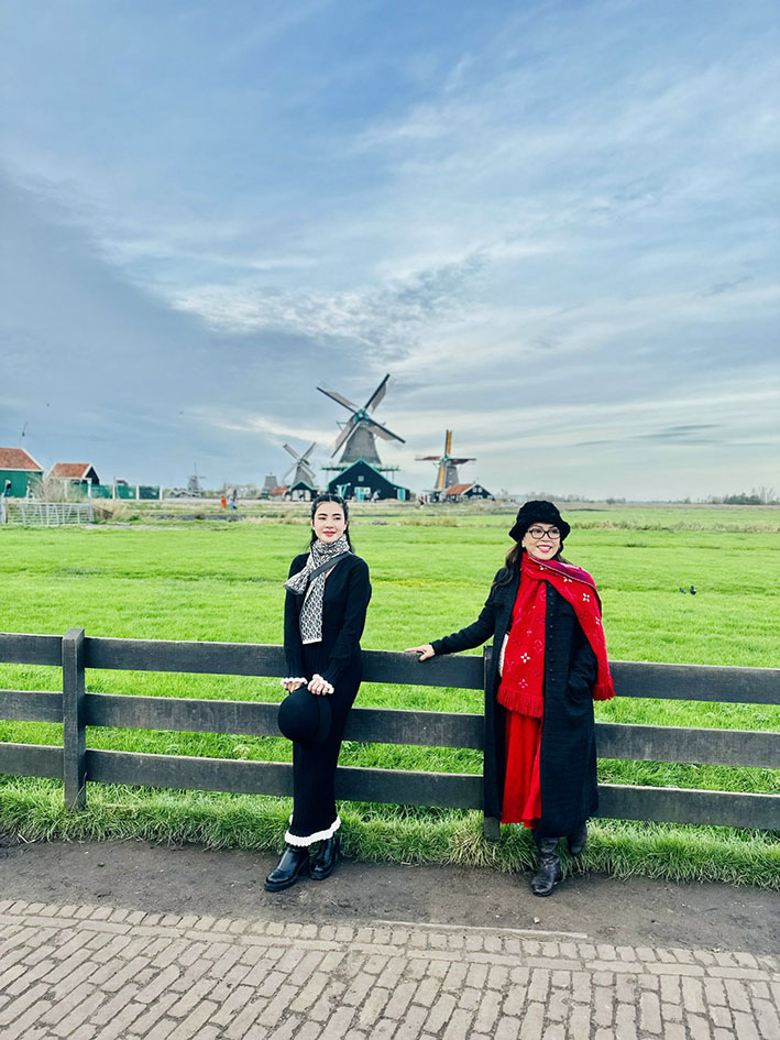 Khách du lịch chụp hình với phía sau là những chiếc cối xay gió ở làng Zaanse Schans.