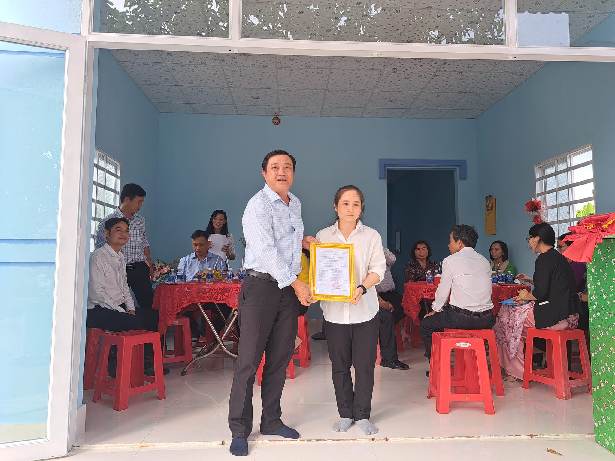 Ông Bùi Minh Dương, Chủ tịch Ủy ban MTTQVN xã Long Tân trao Quyết định tặng nhà đại đoàn kết cho đại diện gia đình bà Nguyệt.