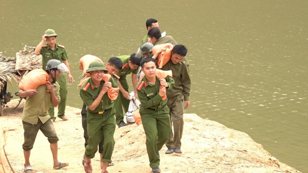 Công an xã cùng các lực lượng đưa vật liệu từ thuyền tập kết trên bờ rồi chở xe mô tô tới từng hộ gia đình để làm móng nhà