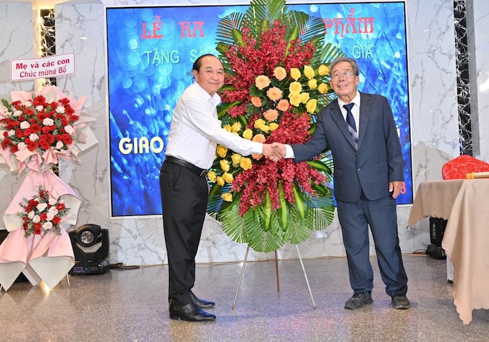 Ông Huỳnh Văn Hồng (bìa trái), Chủ tịch Hội VH-NT tặng hoa chúc mừng tác giả Lê Huy Mậu tại lễ ra mắt.