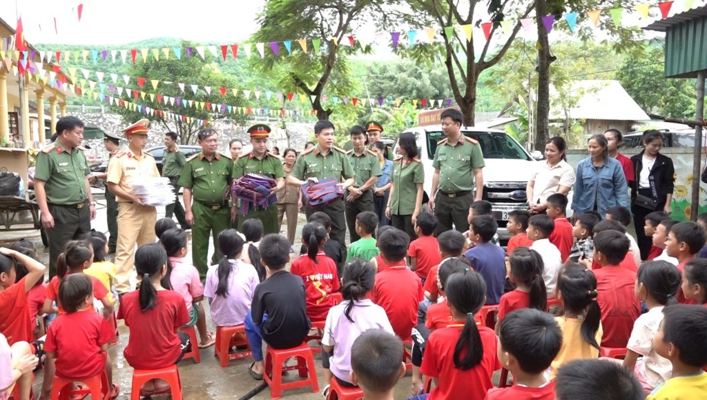Đại tá Trần Hồng Quang – Phó Giám đốc Công an tỉnh trao quà cho các em học sinh bị nước lũ cuốn trôi sách vở, đồ đạc
