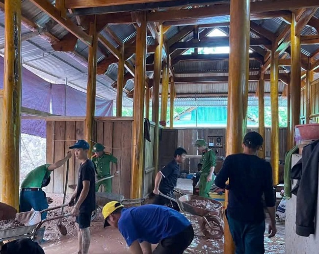 Lực lượng Công an xã phối hợp chính quyền địa phương giúp dân nạo vét bùn đất tràn vào nhà