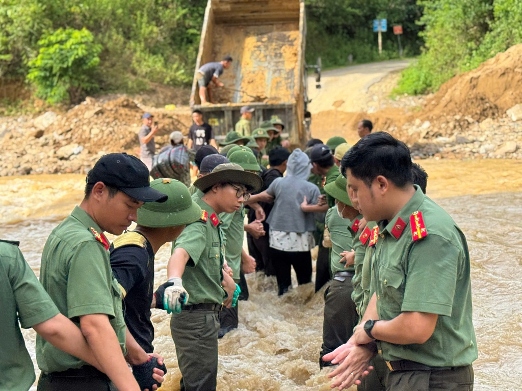 Tổ công tác số 1 Công an tỉnh Nghệ An tạo thành 02 hàng nối dài, đứng vững giữa dòng nước xiết để làm “hàng rào” che chắn, giúp gia đình sản phụ Moong Thị Cường đến Trạm y tế an toàn