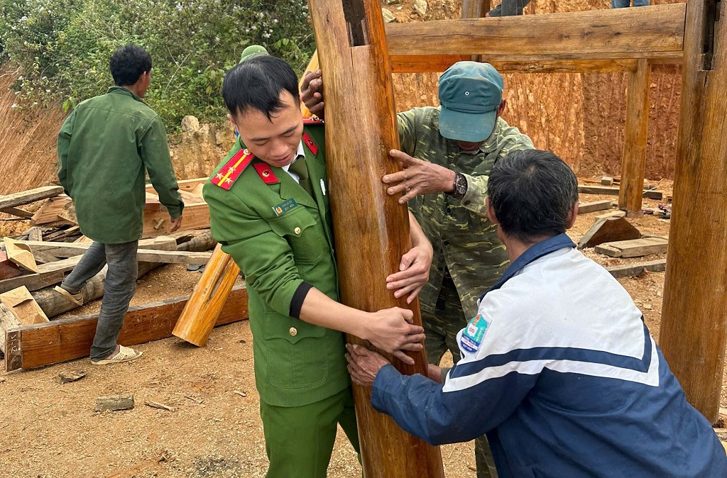 Cán bộ, chiến sĩ Công an xã phối hợp với ban, ngành, tổ chức đoàn thể cùng người dân dựng cột, lắp khung nhà, góp sức giúp hộ gia đình sớm ổn định chỗ ở
