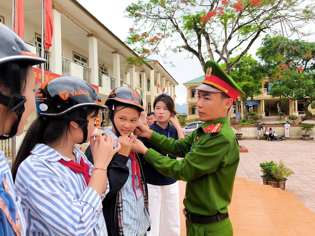 Công an xã Giai Xuân hướng dẫn học sinh đội mũ bảo hiểm đúng cách