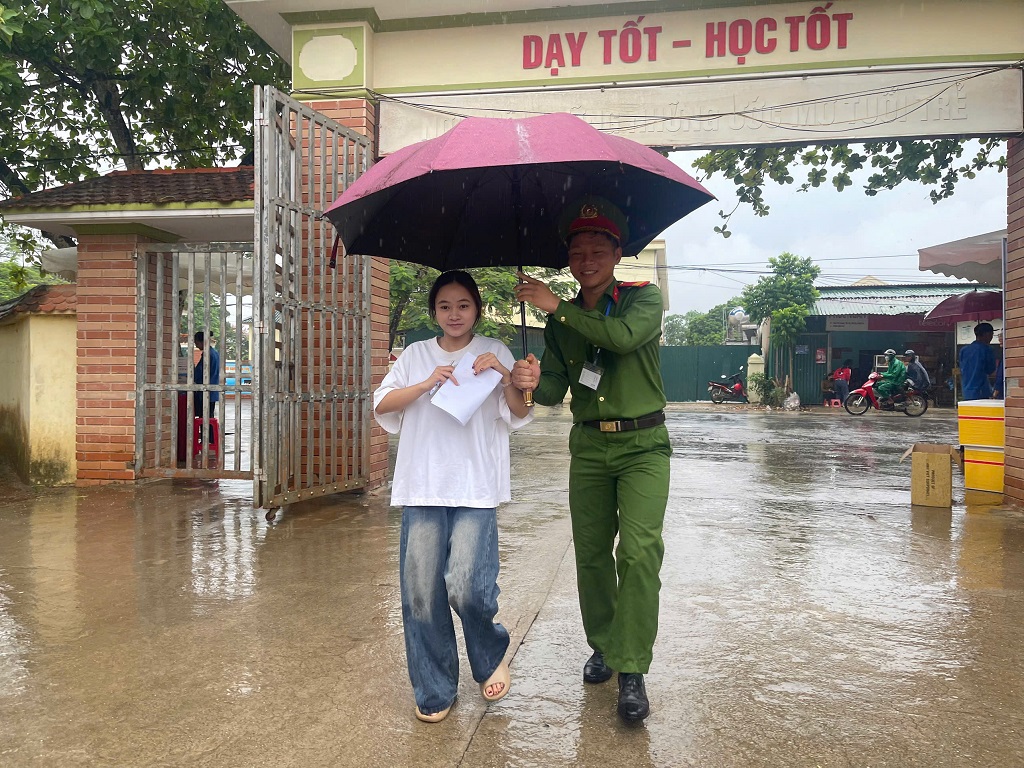 Trong điều kiện thời tiết mưa, thí sinh được Công an xã Tân An hỗ trợ ô che đưa vào phòng thi an toàn