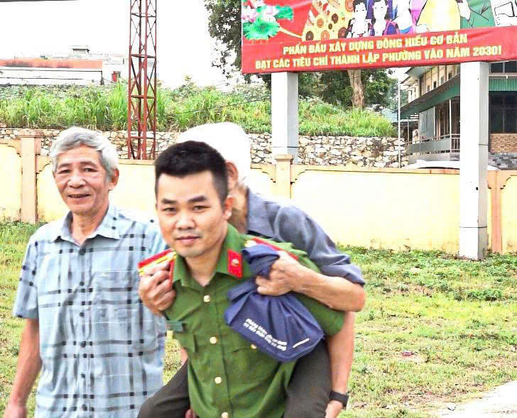 Công an xã  hỗ trợ người già - là thân nhân liệt sĩ đến điểm thu nhận mẫu sinh phẩm ADN