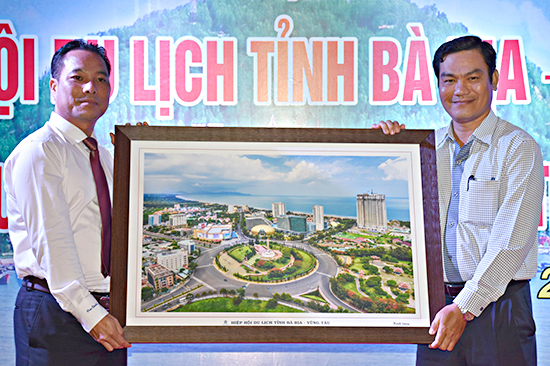Ông Phạm Ngọc Hải (trái), Chủ tịch Hiệp hội Du lịch tỉnh tặng quà lưu niệm cho ông Nguyễn Văn Thương, Phó Chủ tịch UBND TP. Bến Tre.